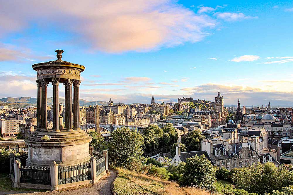 Una vista panoramica di Edimburgo, Scozia da Calton Hill, con il monumento a Dugald Stewart in primo piano e il paesaggio urbano con edifici storici e il Castello di Edimburgo sullo sfondo: un momento perfetto per la tua prossima offerta viaggio in Scozia con SBS Viaggi.
