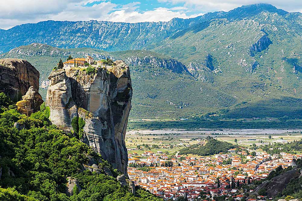 Un monastero si trova in cima a una ripida formazione rocciosa, che domina una città tentacolare e un paesaggio montuoso, in attesa di essere scoperto. Per un'offerta viaggio in Grecia indimenticabile, esplora questo maestoso sito con SBS Viaggi.