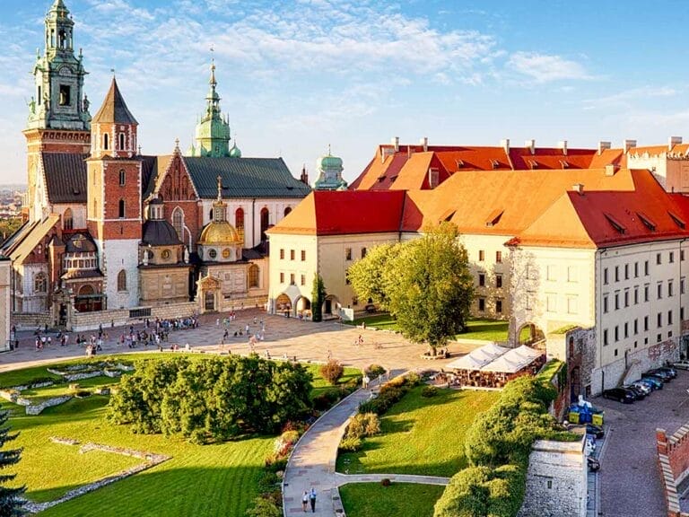 Veduta aerea del Castello di Wawel a Cracovia, Polonia. Il complesso del castello comprende edifici gotici e rinascimentali, prati verdi e percorsi con persone che passeggiano nel cortile soleggiato: un vero highlight per ogni appassionato della Polonia nel suo Gran Tour.