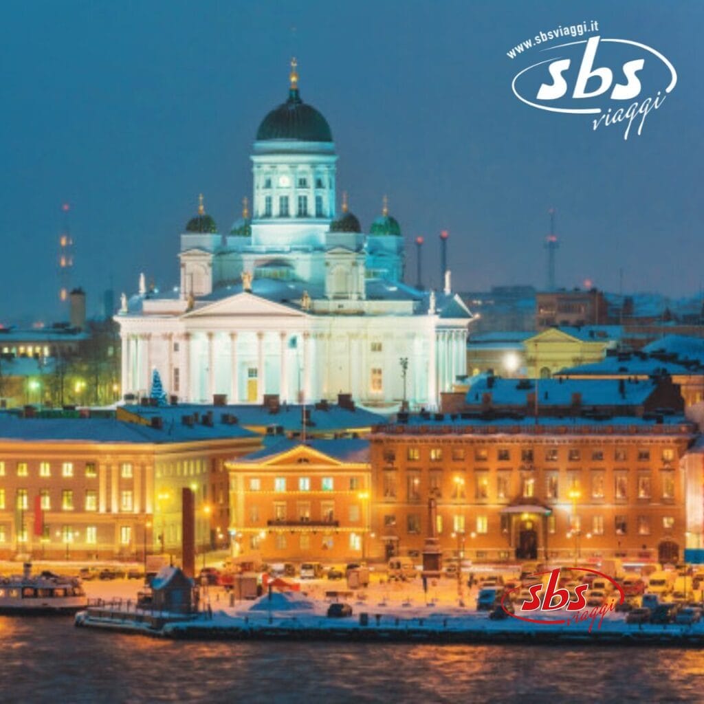 Vista notturna della Cattedrale di Helsinki illuminata, che proietta un'aura magica sugli edifici innevati e sulle luci della città della capitale nordica.