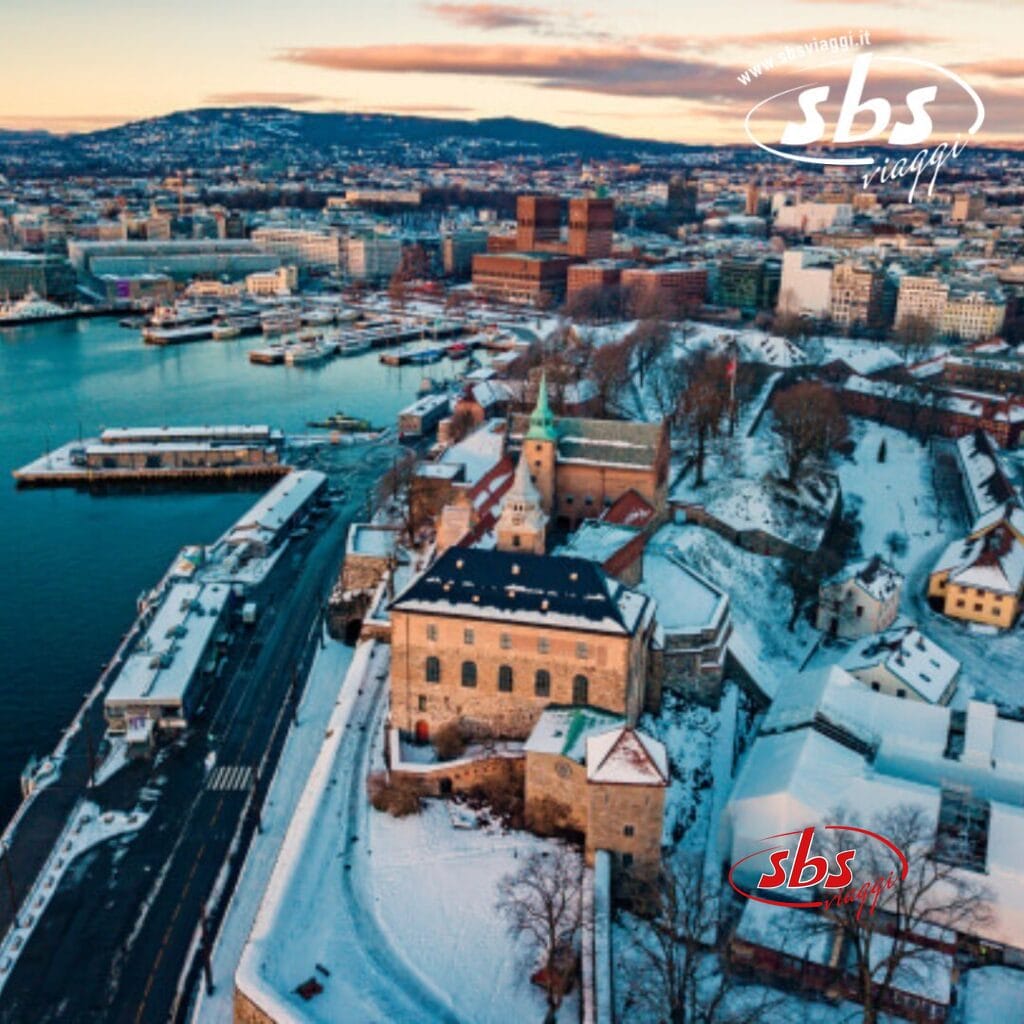 Vista aerea di un paesaggio urbano innevato con lungomare, edifici storici e colline sullo sfondo, che ricordano il fascino incantevole di Fiordi.