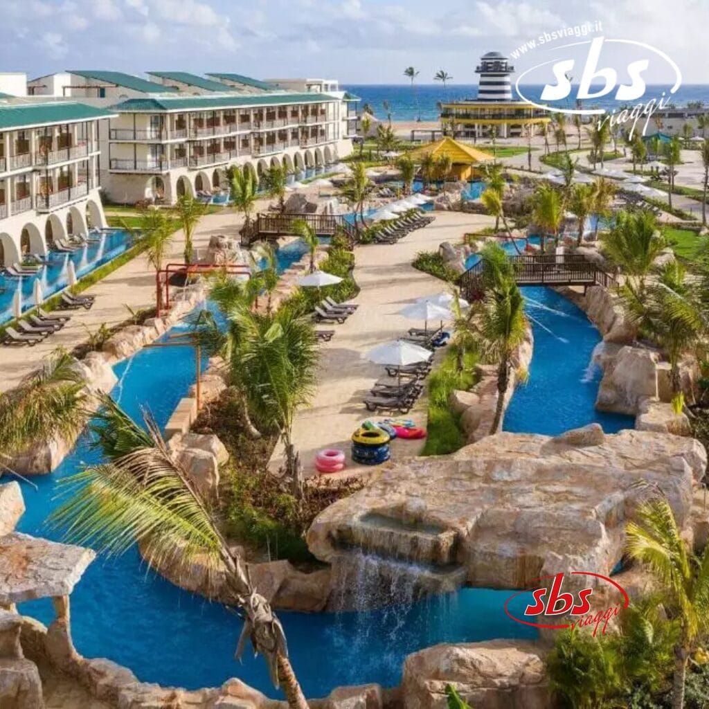 Un resort con piscina tortuosa, sedie a sdraio e palme invita al relax. Sullo sfondo, edifici e uno scorcio dell'oceano esaltano la vista panoramica. È come una bozza automatica del paradiso scritta dalla natura stessa.