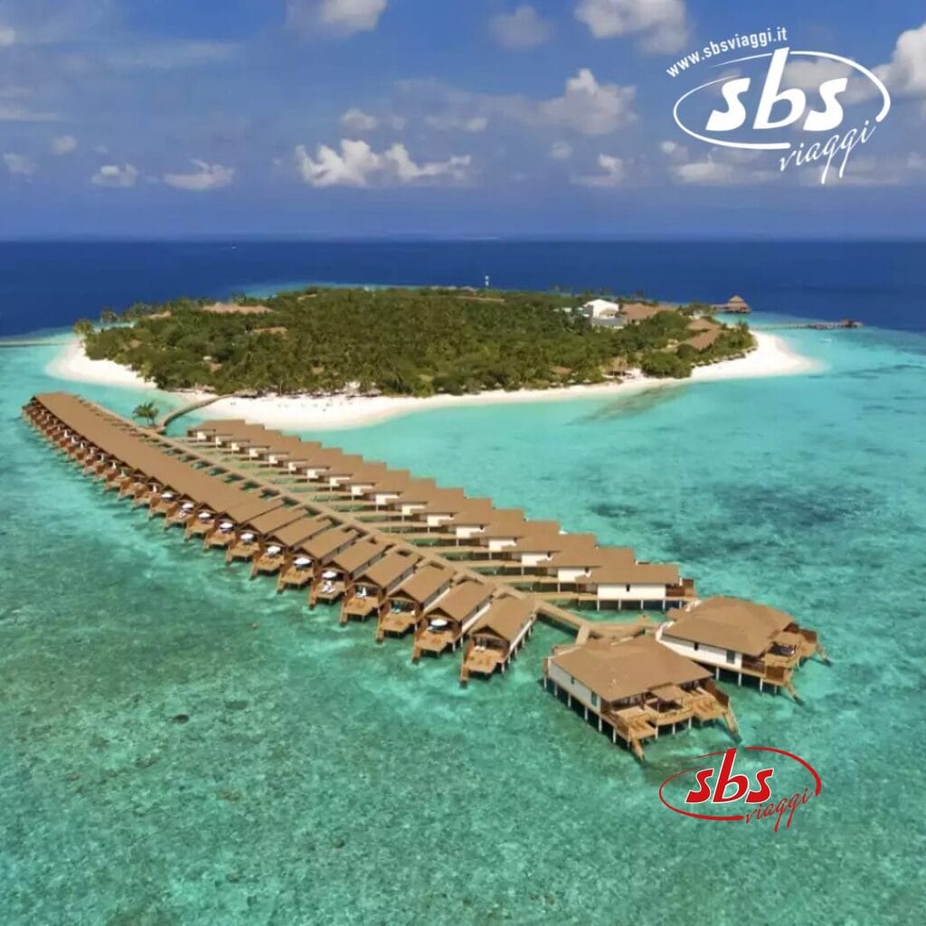 Vista aerea del Reethi Faru Resort, che mette in mostra i suoi bungalow sull'acqua e le spiagge di sabbia bianca circondate da un oceano azzurro e limpido.