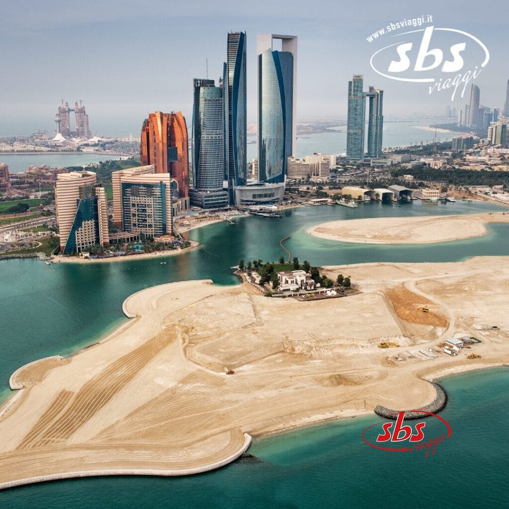 Vista aerea di una città costiera negli Emirati Arabi Uniti, con moderni grattacieli, cantieri edili e una piccola isola con edifici vicino al lungomare, che cattura le meraviglie della sua architettura innovativa.