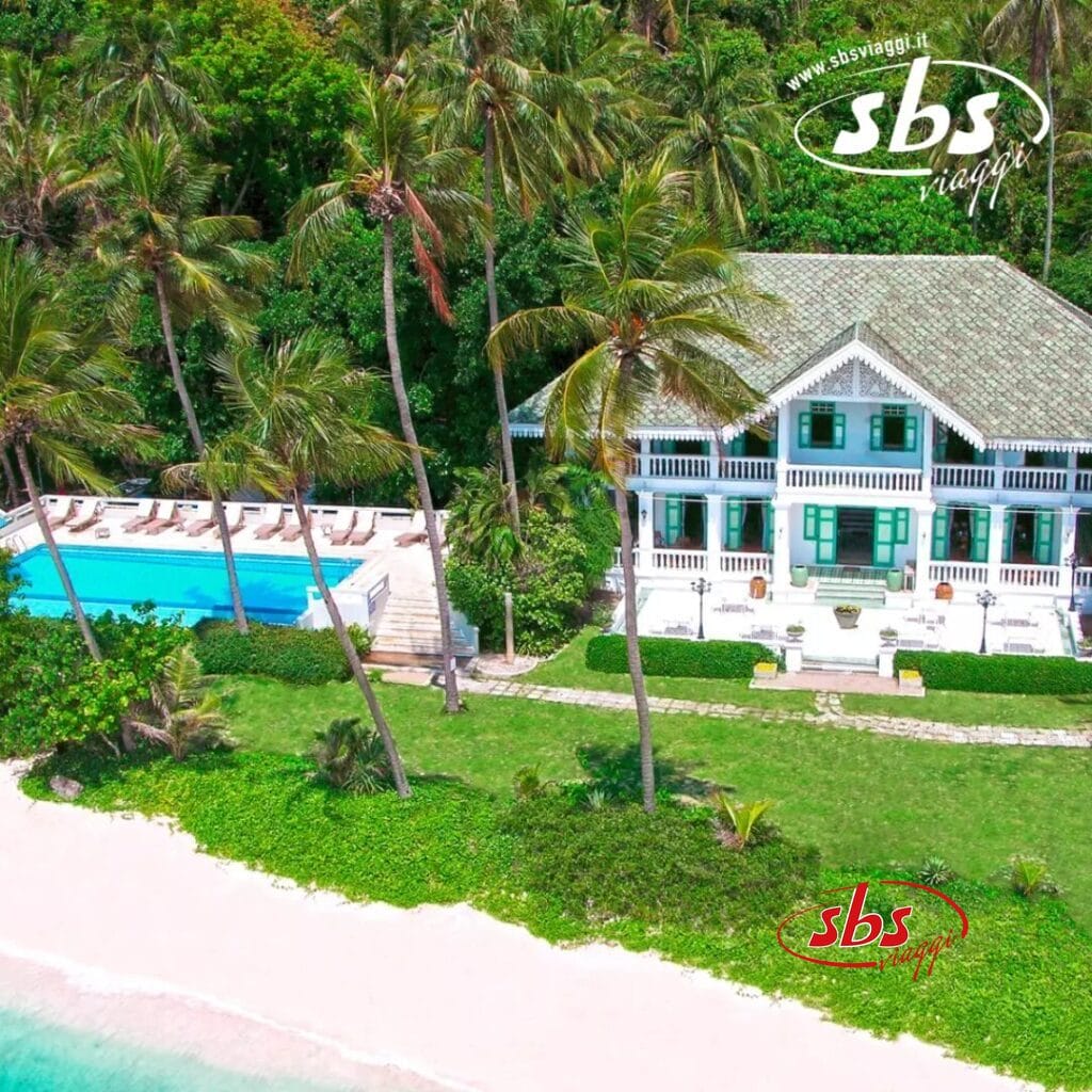 Vista aerea di una villa fronte mare con piscina, circondata da palme e vegetazione lussureggiante. Godetevi la perfetta combinazione di bellezza naturale e design bozza automatica. Una spiaggia di sabbia bianca e un mare turchese si estendono invitanti in primo piano.