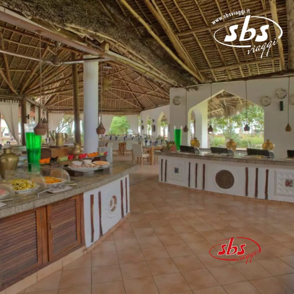 Questa zona buffet all'aperto del Bluebay Beach Resort è caratterizzata da un affascinante tetto di paglia, un elegante pavimento piastrellato e diverse postazioni di ristorazione. Bevande verdi e bianche vi attendono nei dispenser, con tavoli e sedie perfettamente disposti per cenare nel sereno ambiente del resort sulla spiaggia.