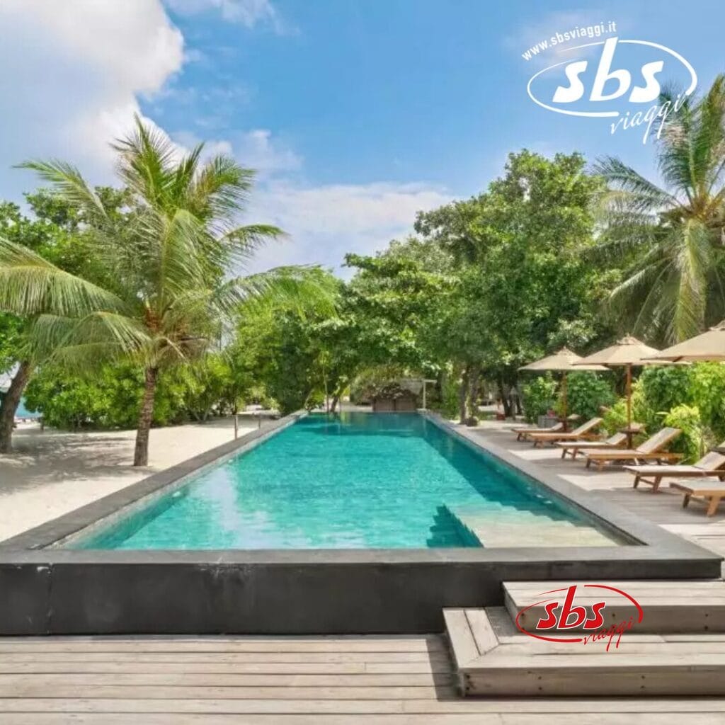 Presso il Barefoot Eco Hotel, su una terrazza in legno, è presente una piscina rettangolare circondata da palme e lettini prendisole, con una spiaggia sabbiosa sullo sfondo.