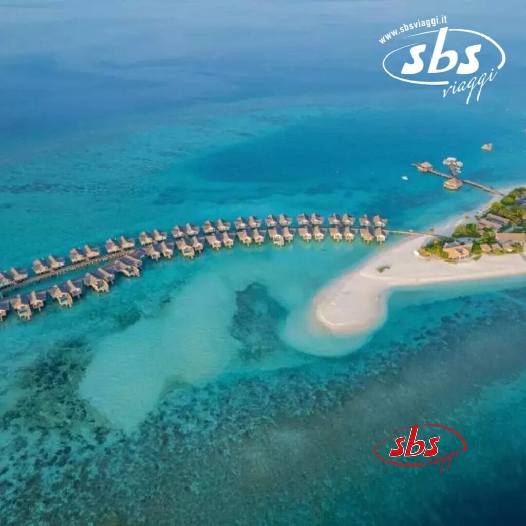 Vista aerea del Cora Cora Maldives, un resort di lusso sull'isola con bungalow sull'acqua, circondato da acque turchesi e vivaci barriere coralline.