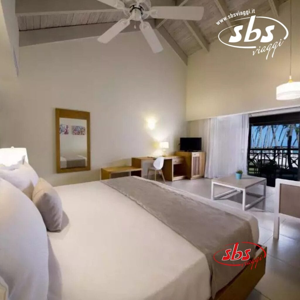 Rilassati in una camera d'albergo Vista Sol con un grande letto, scrivania e sedia. Goditi il balcone con vista sulle splendide palme di Punta Cana e sull'oceano. Ventilatore a soffitto e lampade forniscono un'illuminazione perfetta. Vivi l'atmosfera tranquilla di questo resort sulla spiaggia di prima qualità.