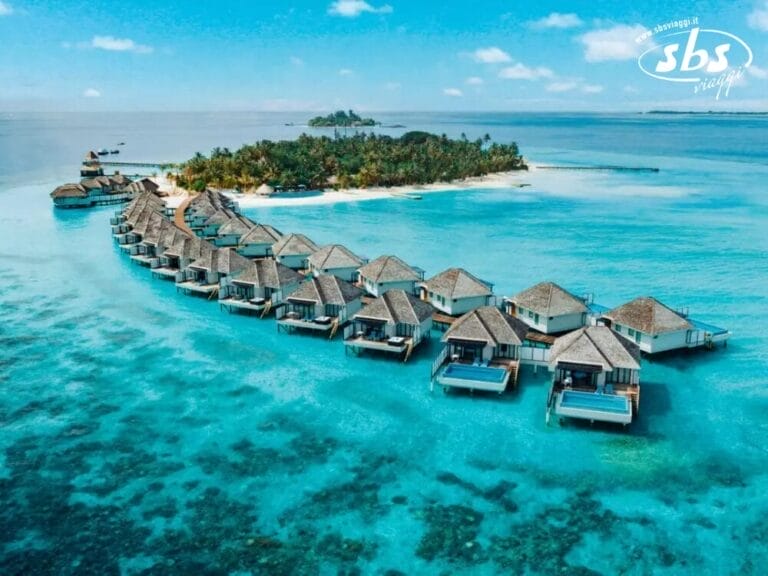 Vista aerea dei bungalow sull'acqua immersi in un oceano turchese, che conducono alla lussureggiante vegetazione dell'isola di Vakarufalhi, incastonata nell'incantevole Nova Maldives.