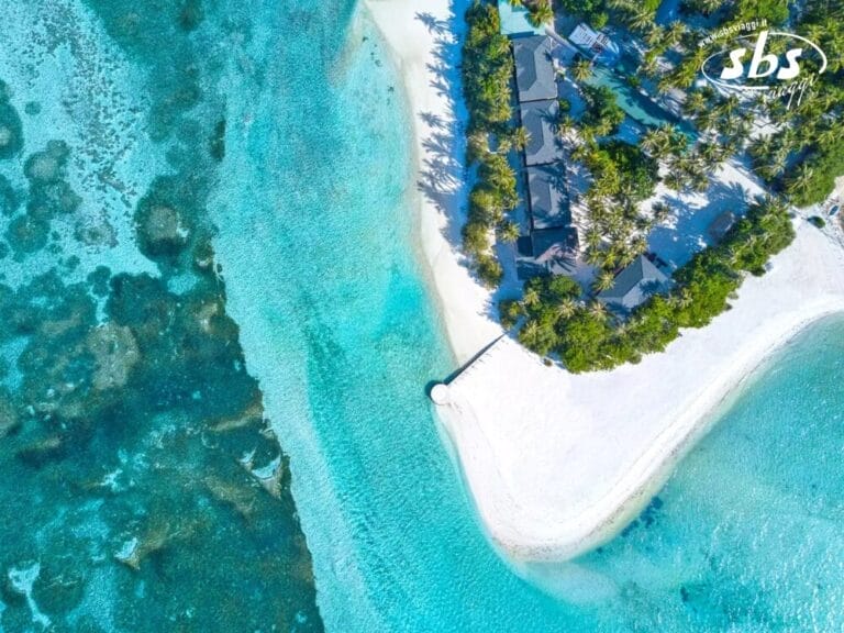 Il Pearl Sands Boutique Hotel offre una vista aerea senza pari di un'isola tropicale con acque turchesi, spiagge sabbiose e fitte palme. Uno stretto molo si estende serenamente nell'oceano, invitando all'esplorazione e alla tranquillità.