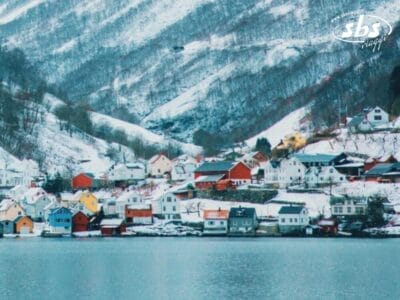 Una cittadina con case colorate in riva a un lago, circondata da colline innevate, offre uno scenario pittoresco che ricorda i fiordi nordici, perfetto per una magica festa di Capodanno.