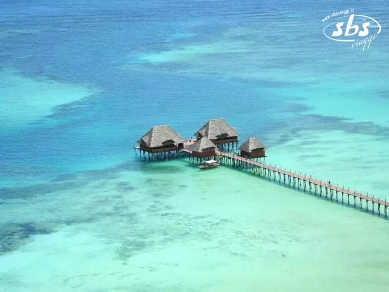 Scoprite l'incantevole fascino di Dongwe, dove i bungalow sull'acqua sono elegantemente collegati da un molo, galleggianti sopra le limpide acque turchesi.