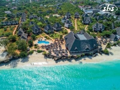 Vista aerea del resort Sunset Beach del Veraclub, con edifici dal tetto di paglia, una piscina centrale e le splendide acque turchesi dell'oceano.