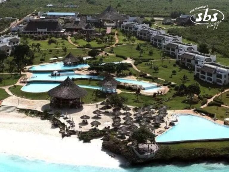 Vista aerea del Seaclub Royal Zanzibar, un resort sulla spiaggia dotato di numerose piscine, rigogliose aree verdi e incantevoli strutture con tetti di paglia vicino all'oceano.