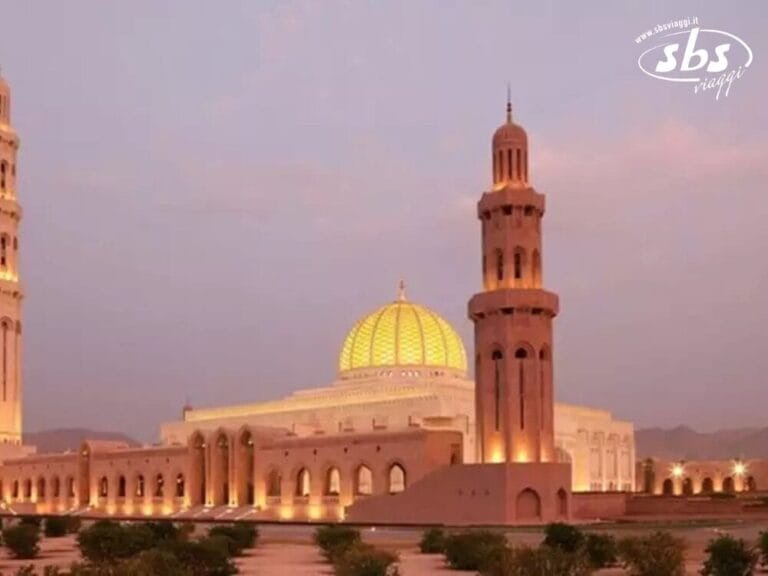 La Grande Moschea del Sultano Qaboos, con la sua grande cupola centrale e l'alto minareto, si erge maestosa contro il cielo crepuscolare, offrendo uno sfondo sereno a chi soggiorna nel vicino Sifawy Boutique Hotel.