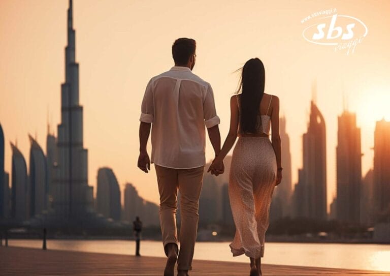 Una coppia che si tiene per mano passeggia sul lungomare al tramonto, con l'iconico skyline di Dubai e l'alta torre sullo sfondo, creando una perfetta atmosfera di San Valentino.