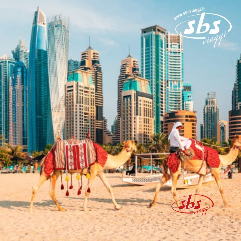 Una persona cavalca un cammello su una spiaggia con lo straordinario skyline di Dubai sullo sfondo.