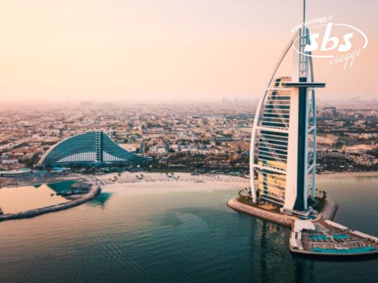 Vista aerea dell'hotel Burj Al Arab di Dubai, con lo straordinario skyline della città e la costa desertica visibili sullo sfondo.