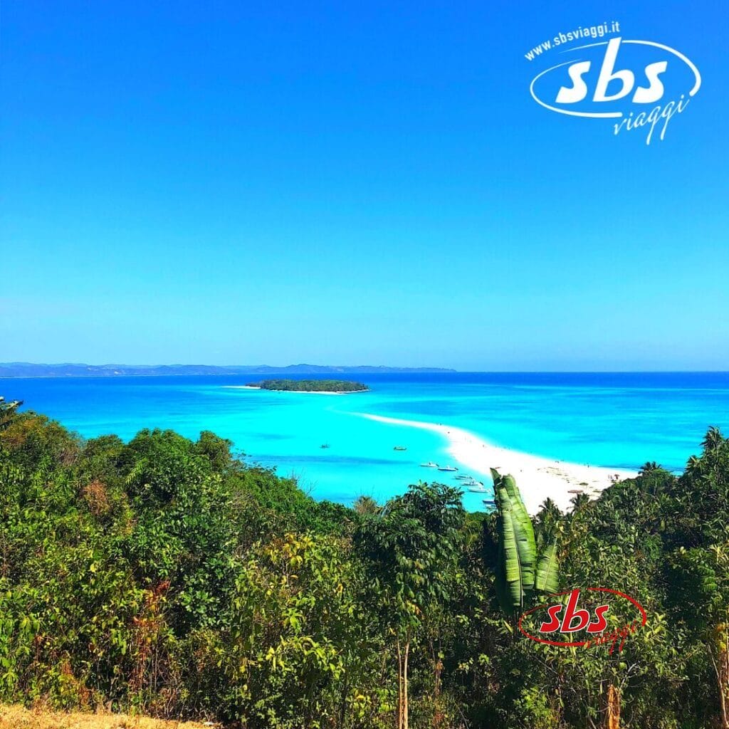 Provate il mix perfetto di avventura e relax mentre ammirate una spiaggia tropicale in Madagascar con acque blu vibranti e vegetazione verde lussureggiante. Il logo 