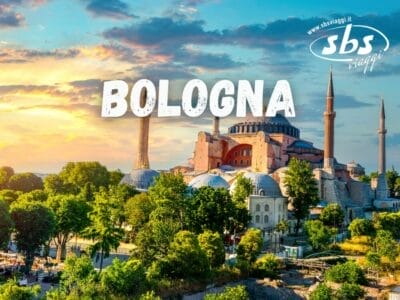 Vista panoramica di un edificio storico con minareti circondato dal verde al tramonto. La sovrapposizione di testo recita "Bologna" con il logo di un'agenzia di viaggi nell'angolo, catturando l'essenza di uno schizzo automatico, o *Bozza automatica*, di momenti tranquilli.