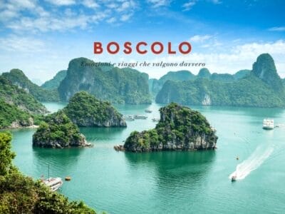Baia turchese con isole calcaree, barche e la scritta "BOSCOLO" sullo sfondo di un cielo azzurro brillante: ecco la bellezza naturale del Vietnam e della Cambogia.
