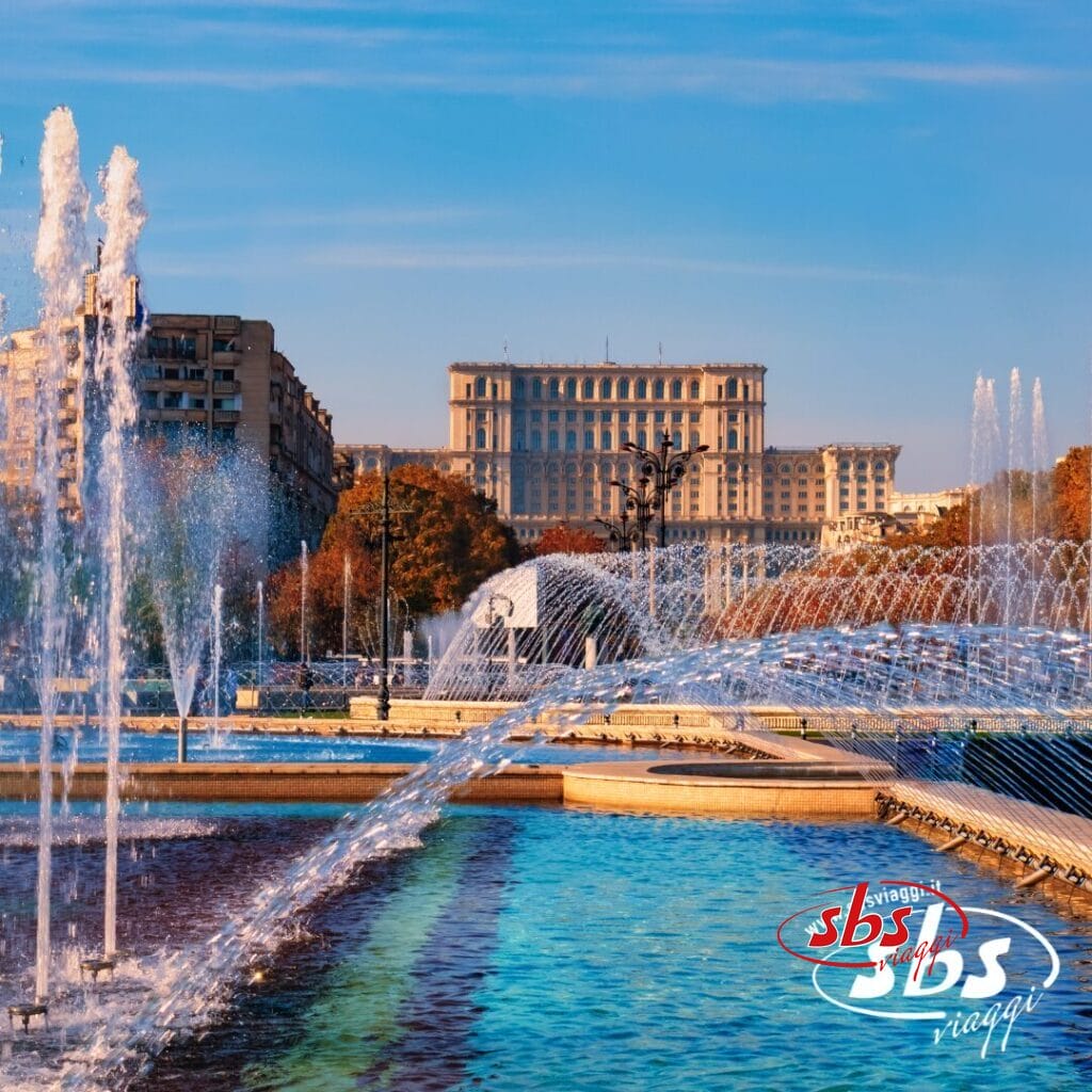 Fontane e piscine in un parco cittadino con un grande edificio storico sullo sfondo; cielo limpido e alberi autunnali visibili: perfetto per chi desidera visitare la Bulgaria o la Romania.