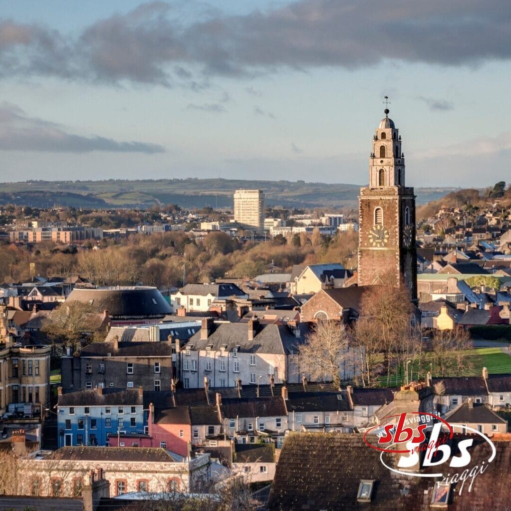 Paesaggio urbano con il campanile della chiesa di Sant'Anna con l'orologio, circondato da edifici e colline sotto un cielo parzialmente nuvoloso, che cattura le bellezze d'Irlanda e ispira viaggi in questa splendida terra.