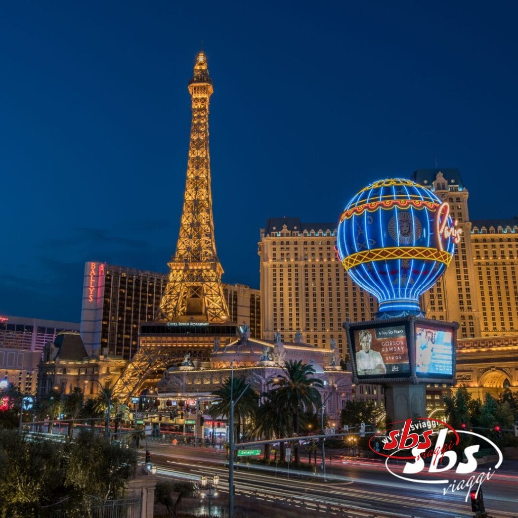 Vista notturna del Paris Las Vegas Hotel con la sua riproduzione della Torre Eiffel e l'insegna illuminata a forma di palloncino, circondato dalle luci della città e dal traffico: una scena vivace che ricorda la vita notturna di Los Angeles.