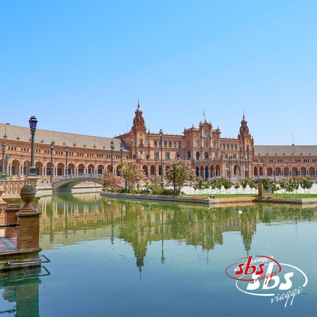 Plaza de España a Siviglia, in Spagna, è una meta turistica imperdibile in Andalusia. Si distingue per un imponente edificio semicircolare con una torre centrale, che circonda una piscina a specchio e ponti. Il logo