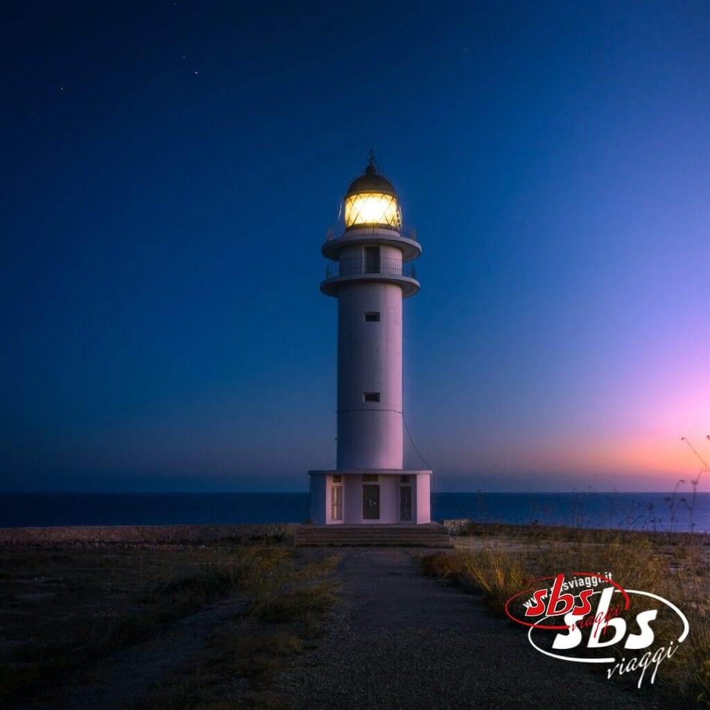Un alto faro bianco con la luce accesa si erge in riva al mare al tramonto, sotto un cielo limpido nell'incantevole isola di Orcadi, con il logo di SBS Viaggi in un angolo: l'ispirazione perfetta per il tuo prossimo Tour Scozia.