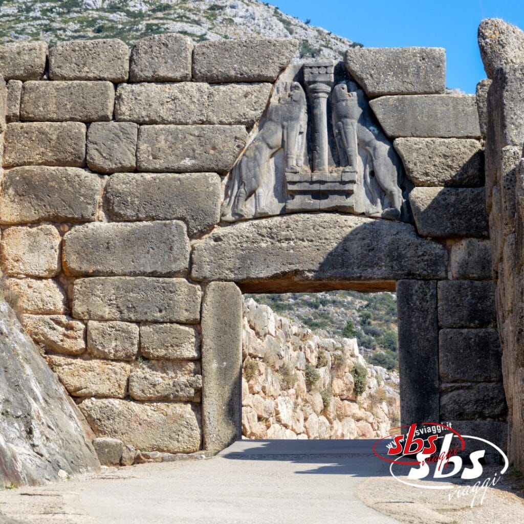 Porta in pietra con un leone scolpito in rilievo sopra l'ingresso, circondata da grandi blocchi di pietra e colline sullo sfondo: un esempio sorprendente della Grecia Classica, perfetto per la tua prossima avventura nel Tour Grecia.