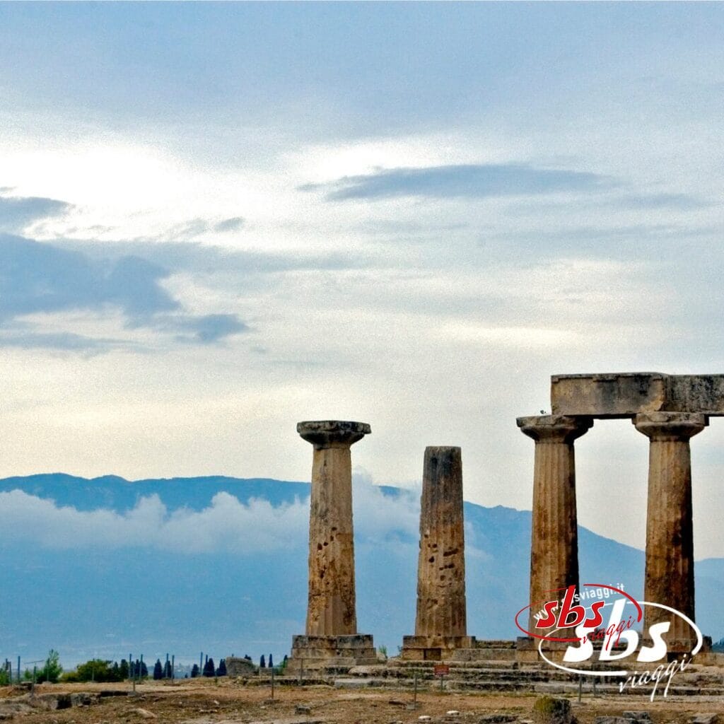 Antiche colonne in pietra di un tempio in rovina si stagliano contro uno sfondo di montagne e un cielo nuvoloso, invitandovi a esplorare le meraviglie di un Tour Grecia Classica.
