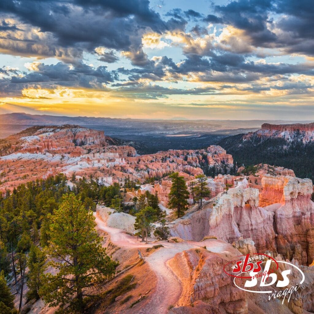 Formazioni rocciose e pini in un canyon al tramonto, con nuvole spettacolari e luce del sole nel cielo, evocano lo spirito del Colorado del 1924; nell'angolo appare il logo
