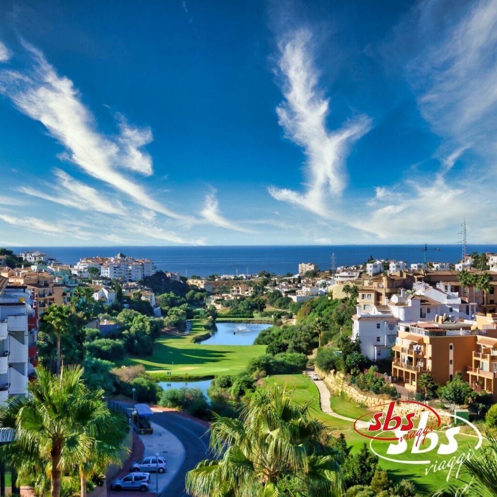 Godetevi la vista panoramica di una città costiera dell'Andalusia, dove edifici e vegetazione lussureggiante circondano un campo da golf incontaminato sotto un cielo azzurro brillante con nuvole leggere. Una tappa perfetta del vostro tour dell'Andalusia per esplorare le sue splendide attrazioni.