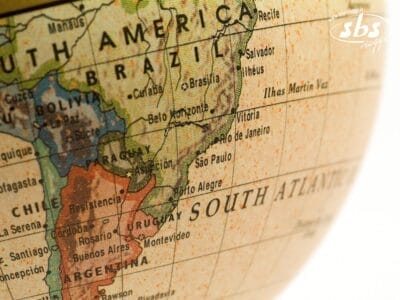Primo piano di un globo che evidenzia il Sudamerica, con Brasile, Argentina, Uruguay e le regioni circostanti chiaramente visibili, insieme ai nomi dei paesi e delle città.