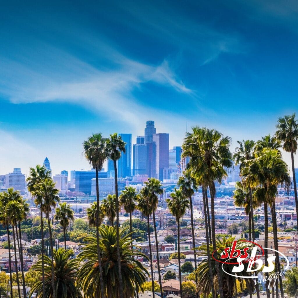 Lo skyline del centro di Los Angeles con alti grattacieli, palme in primo piano e un cielo azzurro e limpido sopra la testa: una vista iconica lungo il Tour del Golden West.