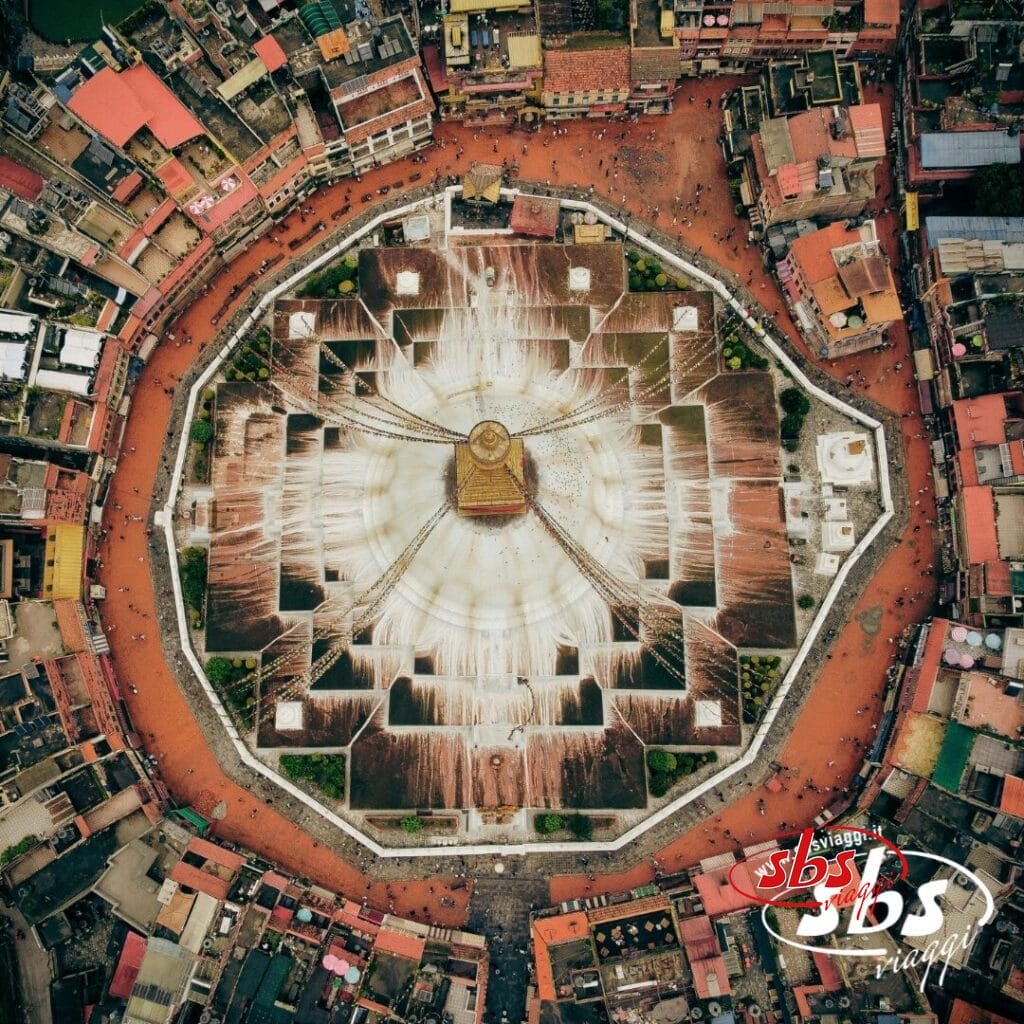 La vista aerea dello Stupa di Boudhanath a Kathmandu, in Nepal, mostra la sua cupola bianca, la guglia dorata e la piazza circolare, un'attrazione iconica di qualsiasi tour in Nepal, in mezzo a edifici densamente popolati.