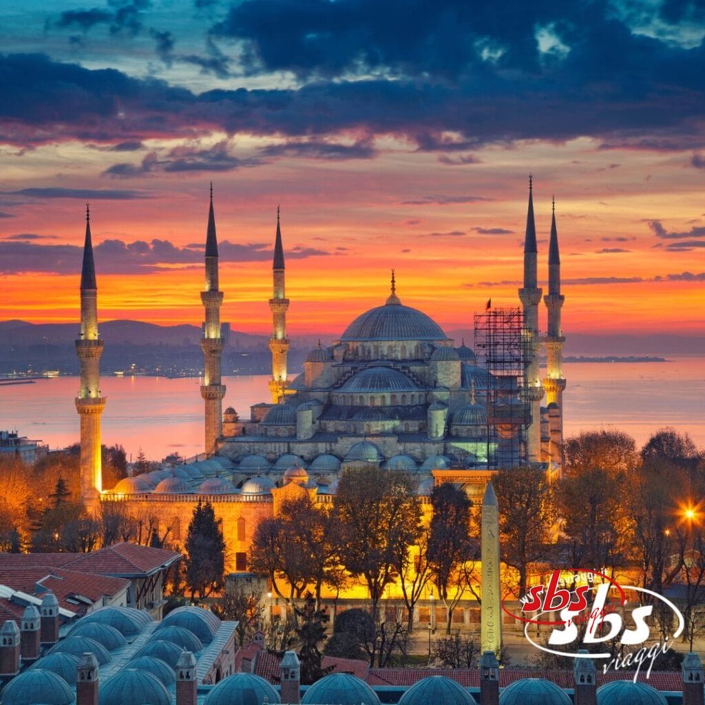 La Moschea Blu di Istanbul al tramonto, con i suoi sei minareti e le cupole illuminate, mostra i Colori della Turchia, anche se le impalcature su un lato lasciano presagire un restauro in corso durante il tuo viaggio Turchia.