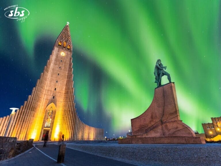 La chiesa di Hallgrimskirkja e la statua di Leif Erikson illuminate dall'aurora boreale a Reykjavik, Islanda Viva, Islanda di notte.