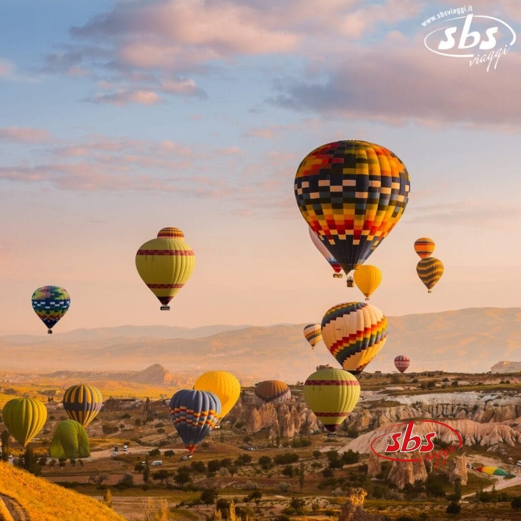 Coloratissime mongolfiere fluttuano su un paesaggio roccioso e panoramico all'alba, sotto un cielo limpido: uno spettacolo indimenticabile durante il Tour della Turchia.