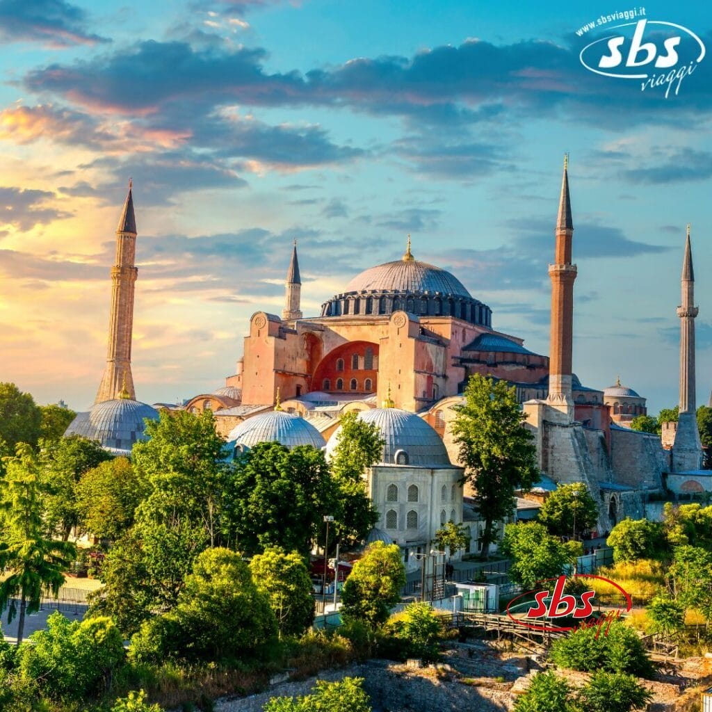 La Basilica di Santa Sofia a Istanbul, con i suoi alti minareti, circondata da alberi sotto un cielo colorato al tramonto, è un maestoso esempio di Bozza automatica.