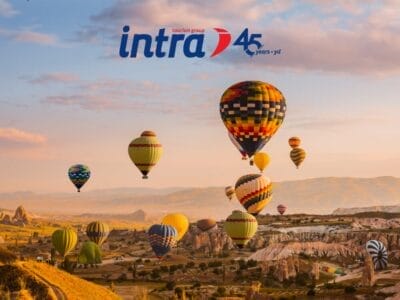 All'alba, coloratissime mongolfiere si librano sulle colline rocciose, con il logo "intra 45 anni" nel cielo: l'ideale per un Tour della Turchia o per chi cerca un'avventura da Speciale Bari.